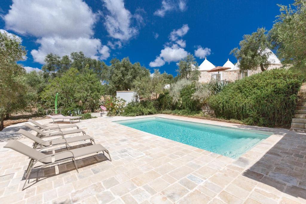 une piscine avec des chaises longues et une piscine dans l'établissement Trullo Lui di Borgo Paoli by Perle di Puglia, à Ceglie Messapica