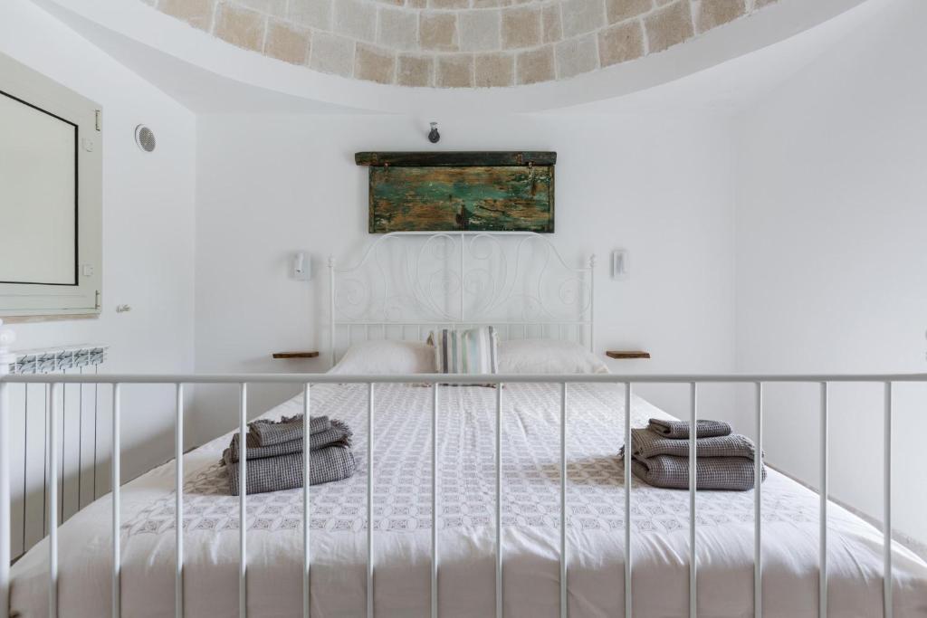 une chambre blanche avec un lit avec une barrière dans l'établissement Trullo Lui di Borgo Paoli by Perle di Puglia, à Ceglie Messapica