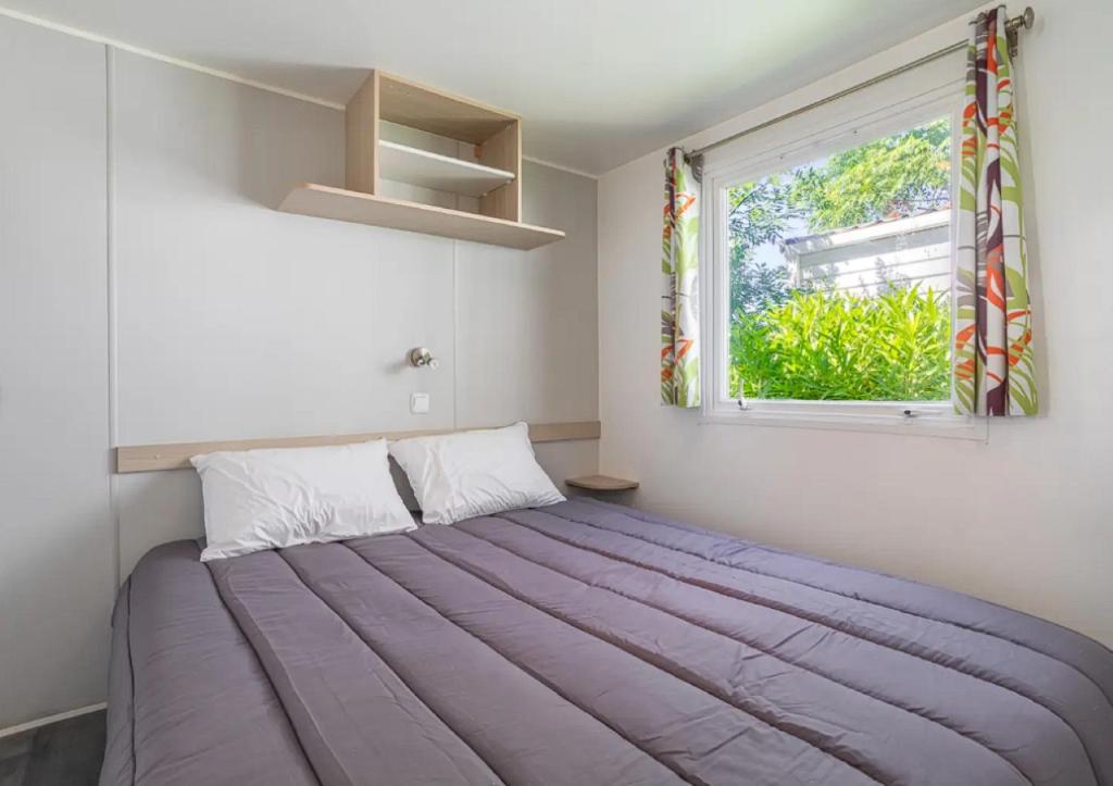 un grand lit dans une chambre avec une fenêtre dans l'établissement Mobil-home de Laura et Angélique au camping ''Le Neptune'' jusqu'à 4 personnes, à Argelès-sur-Mer 17 autres photos