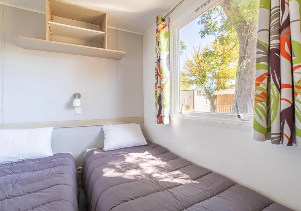 - une chambre avec un canapé et une fenêtre dans l'établissement Mobil-home de Laura et Angélique au camping ''Le Neptune'' jusqu'à 4 personnes, à Argelès-sur-Mer