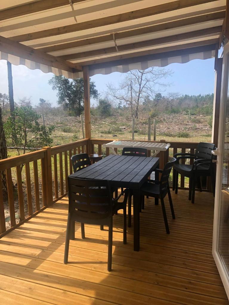 une terrasse en bois avec des tables et des chaises dessus dans l'établissement Les dunes de Contis Chez Edith océan pins et détente assurée dans camping 4 étoiles, à Saint-Julien-en-Born