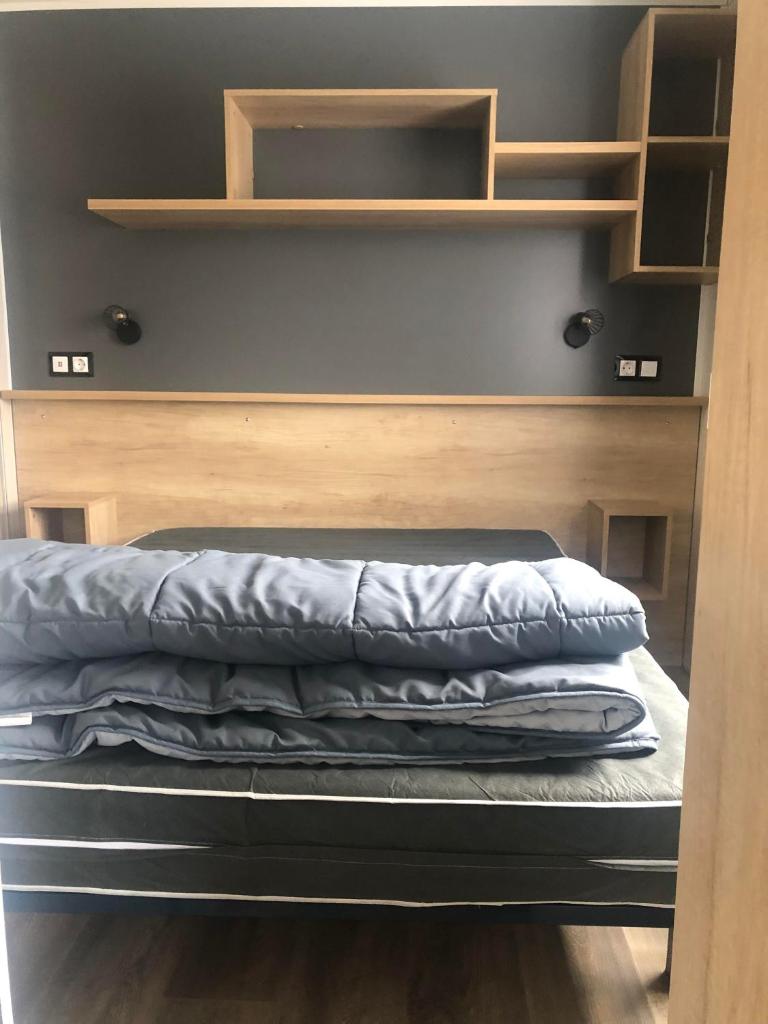 Ce lit se trouve dans un dortoir doté d'étagères en bois. dans l'établissement Les dunes de Contis Chez Edith océan pins et détente assurée dans camping 4 étoiles, à Saint-Julien-en-Born