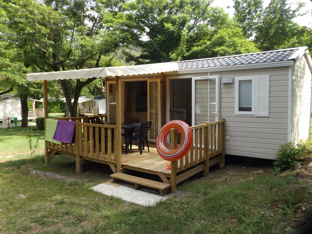 une petite maison avec une terrasse et une table dans l'établissement SUN Camping, à Sampzon 3 autres photos