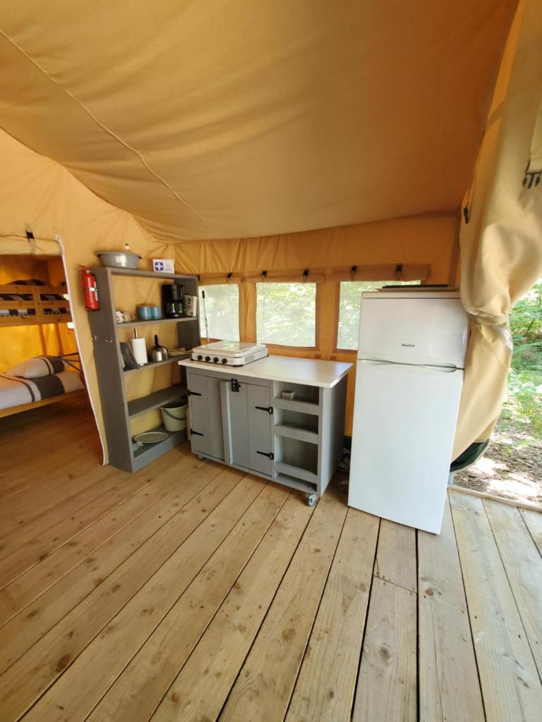 - une cuisine dans une tente avec un réfrigérateur et une cuisinière dans l'établissement Tente des bois, à Rouffignac-Saint-Cernin-de-Reilhac