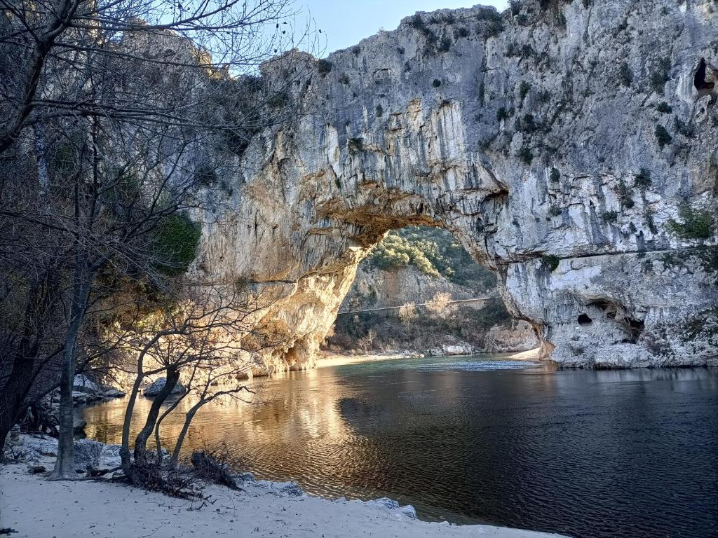 une arche dans une falaise rocheuse au-dessus d'une rivière dans l'établissement SUN Camping, à Sampzon