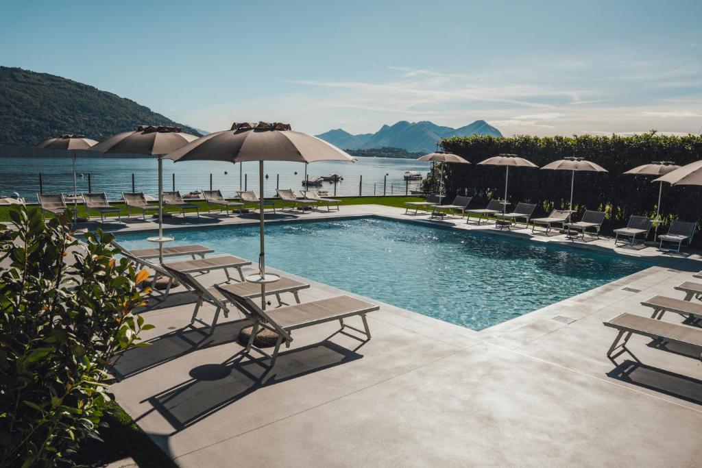 une piscine avec des chaises et des parasols au bord de l'eau dans l'établissement Lago Maggiore Bay, à Baveno