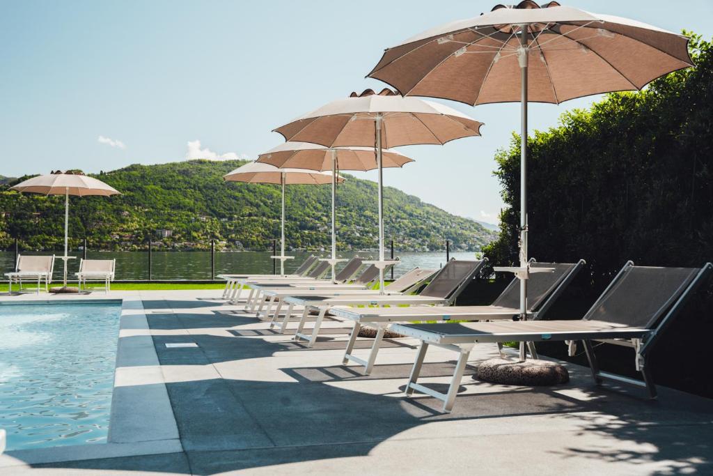 une rangée de tables avec des parasols à côté d'une piscine dans l'établissement Lago Maggiore Bay, à Baveno