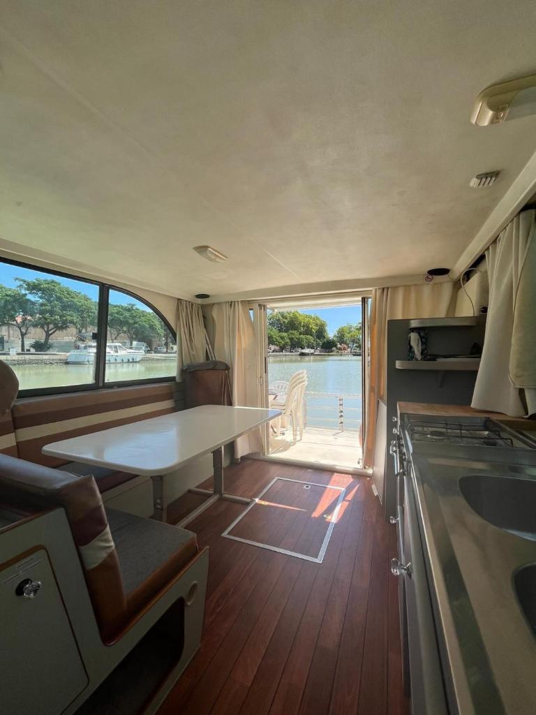 une cuisine avec une table au milieu d'un bateau dans l'établissement Bateau 6 personnes sans permis terrasse à quai ou option navigation, à Béziers