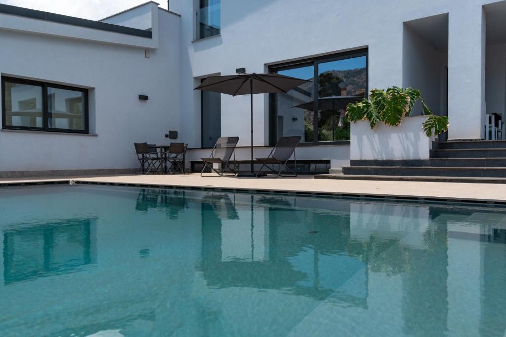 - une piscine avec des chaises et un parasol à côté d'une maison dans l'établissement Villa Tina Mondello, à Mondello