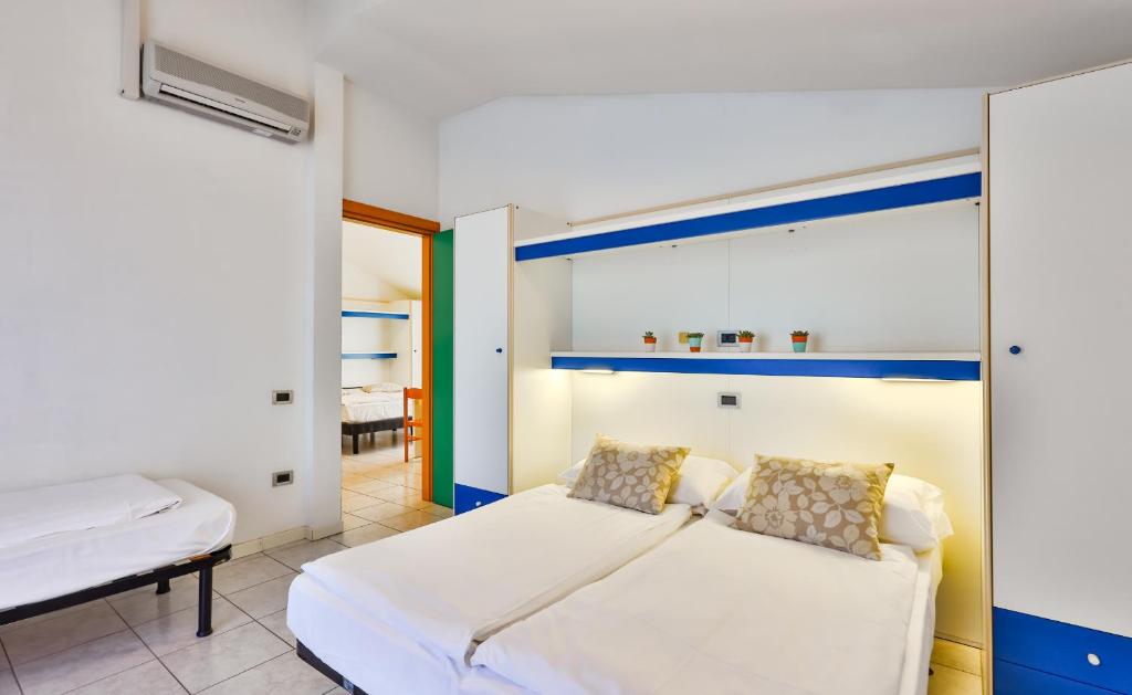 une chambre avec un lit blanc et un miroir dans l'établissement Aparthotel Carinzia, à Lignano Sabbiadoro