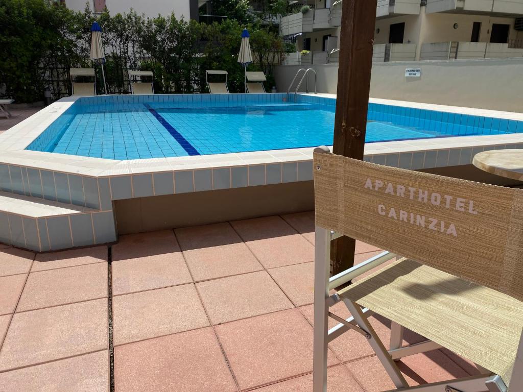 une chaise assise en face d'une piscine dans l'établissement Aparthotel Carinzia, à Lignano Sabbiadoro