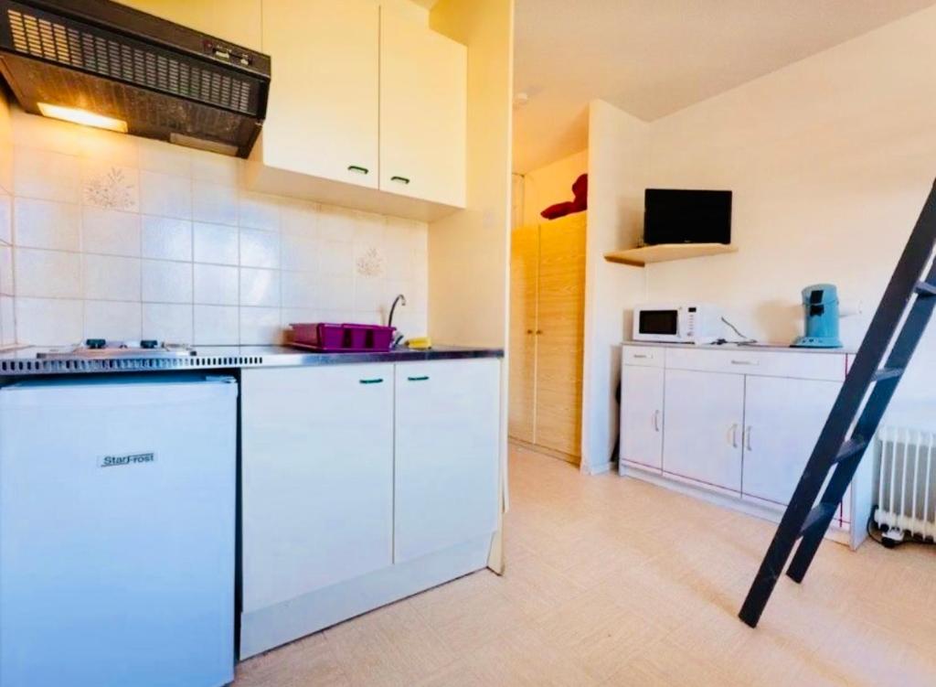 une cuisine avec des armoires blanches et une cuisinière dans l'établissement Exceptionnel Studio Le petit dortoir wifi parking gratuit vue incroyable sur le pic au pied des pistes de superdevoluy, à Saint-Étienne-en-Dévoluy
