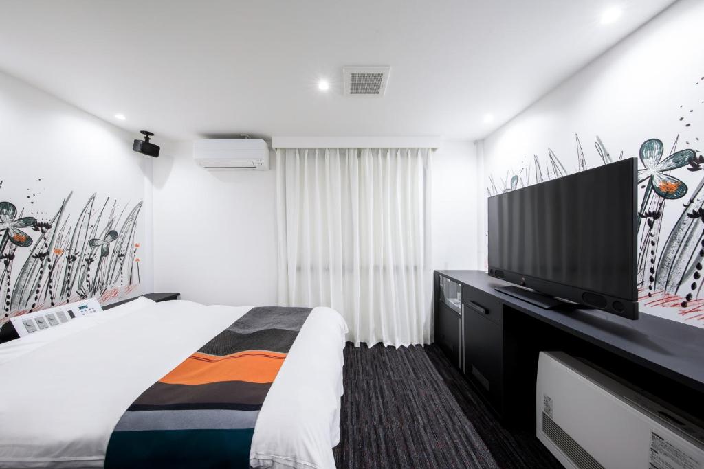 une chambre avec un lit et une télévision à écran plat dans l'établissement HOTEL MONO - Adult only, à Ueda
