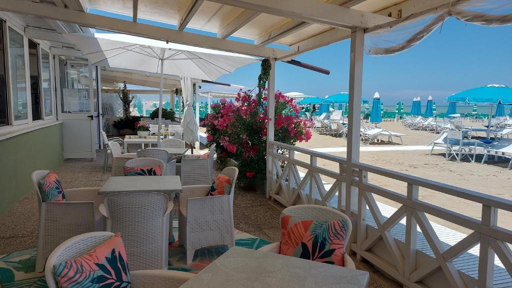 un restaurant sur la plage avec tables et chaises dans l'établissement Albergo Regina, à Senigallia