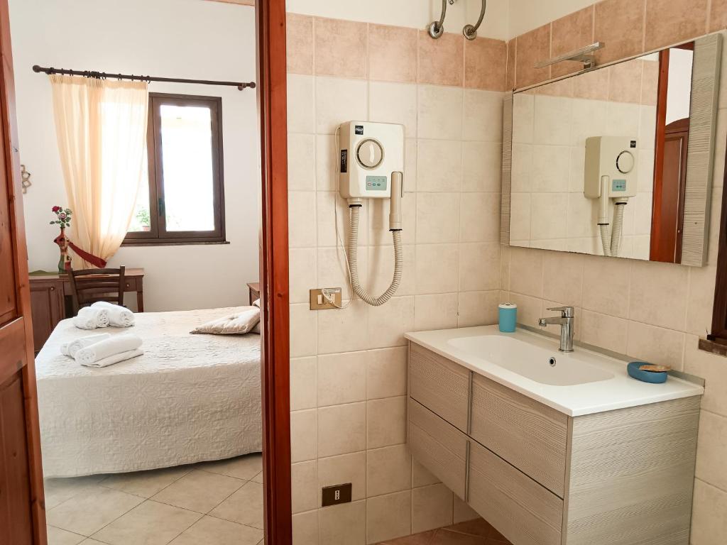 une salle de bain avec un lit, un lavabo et un miroir dans l'établissement Hotel Grotticelli, à Scopello
