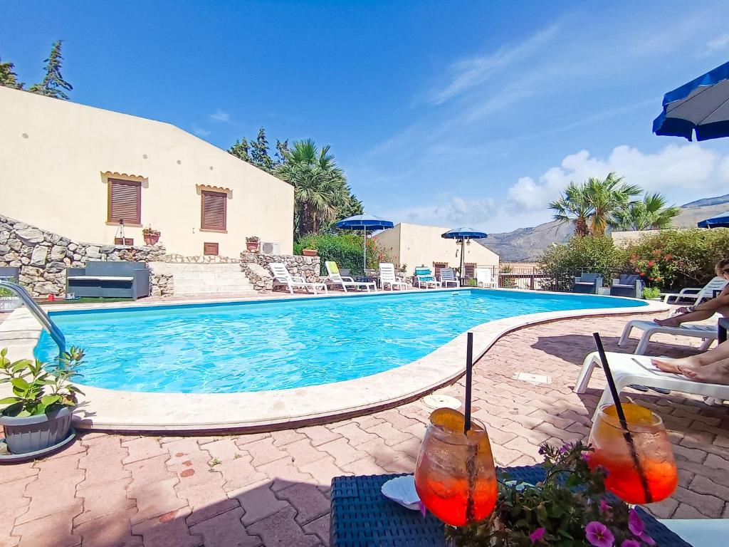 - une piscine avec des chaises longues et des parasols à côté d'un complexe dans l'établissement Hotel Grotticelli, à Scopello