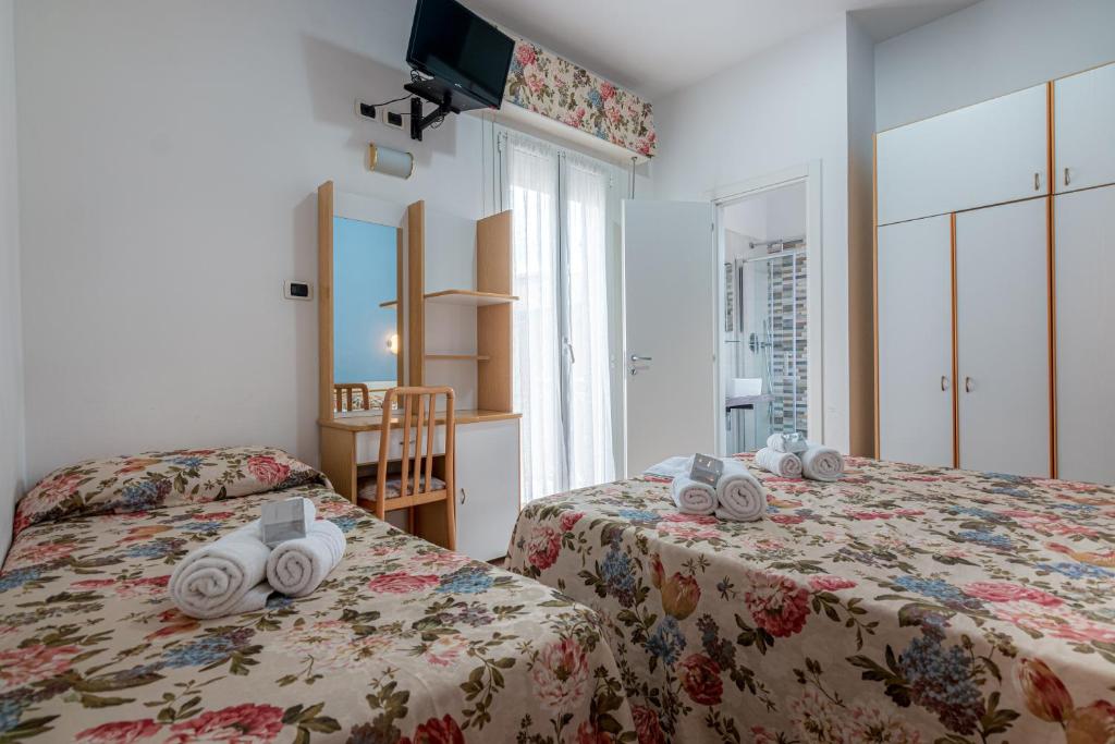 une chambre avec deux lits avec des serviettes dessus dans l'établissement Hotel Ilde, à Rimini
