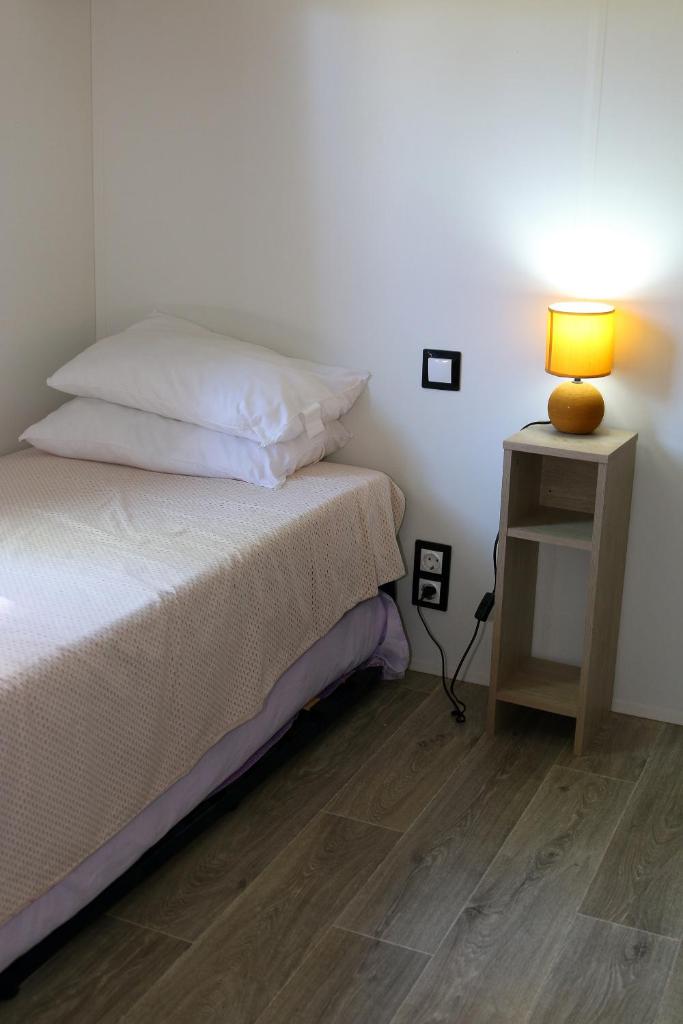 - une chambre avec un lit et une lampe sur une table de chevet dans l'établissement Mobil-home Narbonne-Plage, à Narbonne-Plage