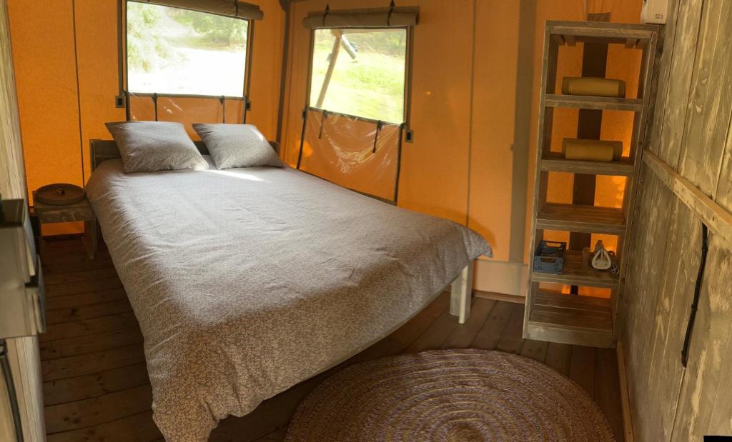 - un lit dans une petite chambre avec 2 fenêtres dans l'établissement Lodge A NASSA, à Olivese