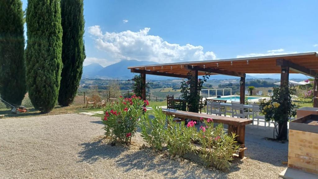un pavillon avec une table, des bancs et des fleurs dans l'établissement Villa Fonte a Colle, à Castorano