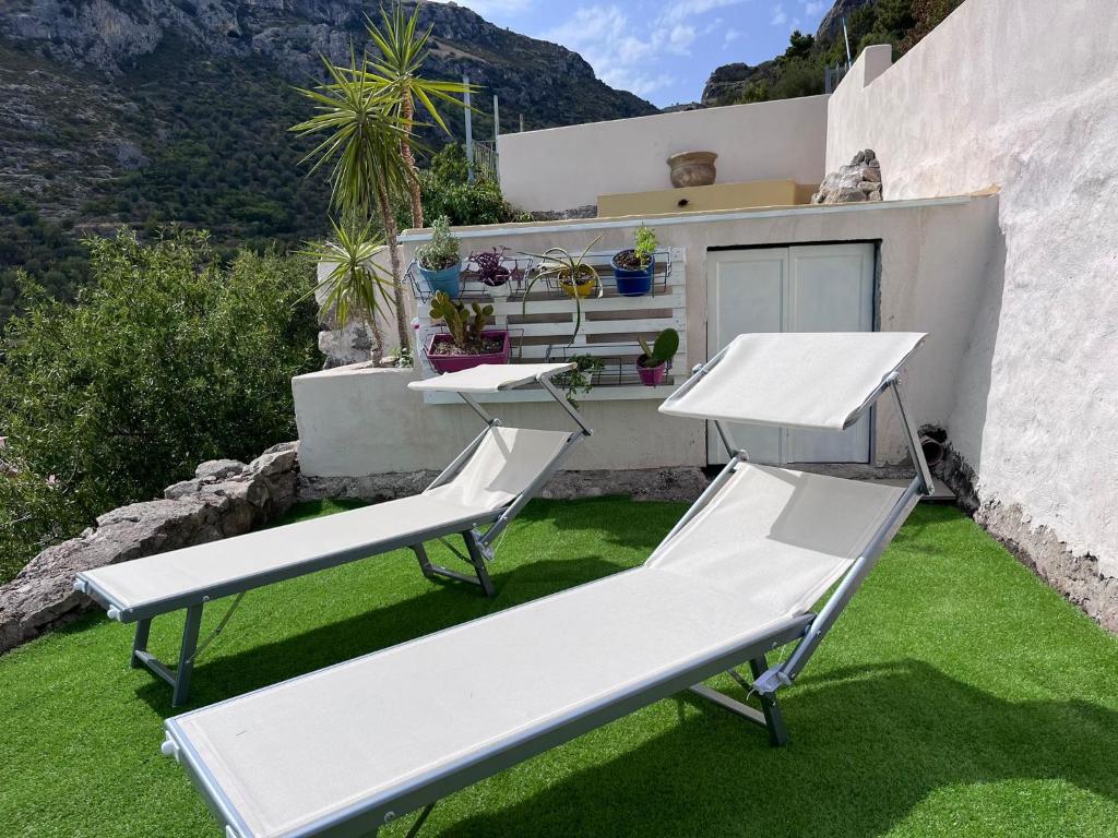 2 chaises blanches et un banc sur une pelouse dans l'établissement Villa Francesca - Manfredi Homes&Villas, à Monte SantʼAngelo