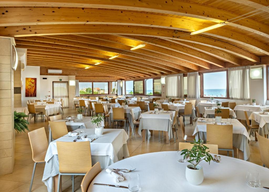 un restaurant avec des tables et des chaises blanches et des fenêtres dans l'établissement Marc Hotel, à Vieste