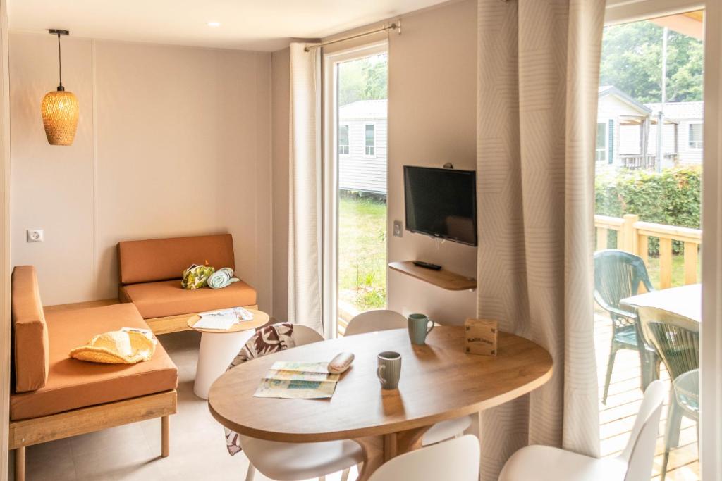 un salon avec une table et un salon avec une fenêtre dans l'établissement Camping Domaine de la Ville Huchet, à Saint-Malo