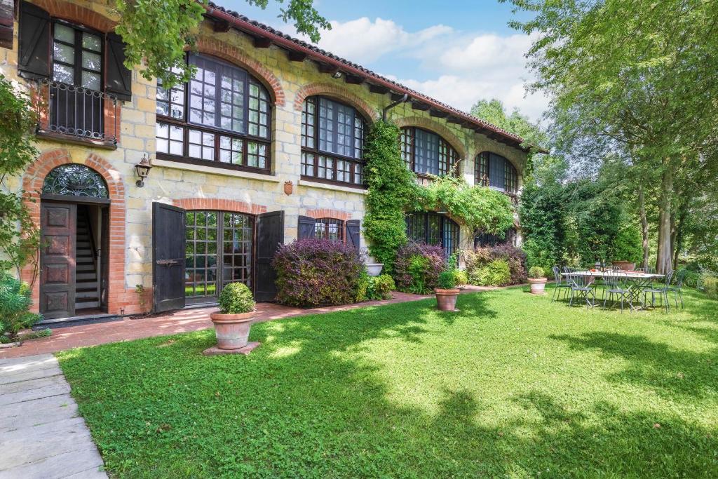 une maison avec une cour avec de l'herbe verte dans l'établissement Il Roseto 10, Emma Villas, à Terruggia