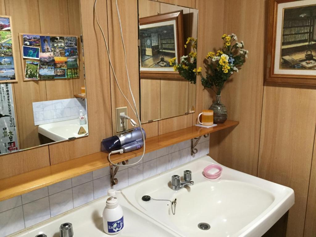 une salle de bain avec un lavabo blanc et un miroir dans l'établissement Tajimaya, à Nakatsugawa 37 autres photos