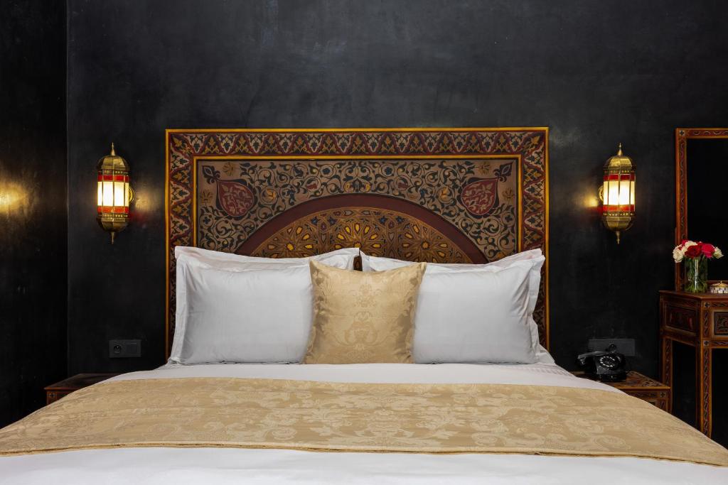 une chambre avec un grand lit avec des oreillers blancs dans l'établissement Alrashid Marrakech - Hotel & SPA, à Marrakech