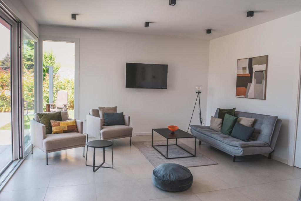 - un salon avec 2 chaises et une télévision murale dans l'établissement Villa My Lagozise, à Pacengo di Lazise