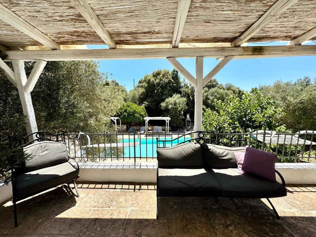 deux canapés sur un patio avec piscine dans l'établissement Trullo Happiness, à Ostuni