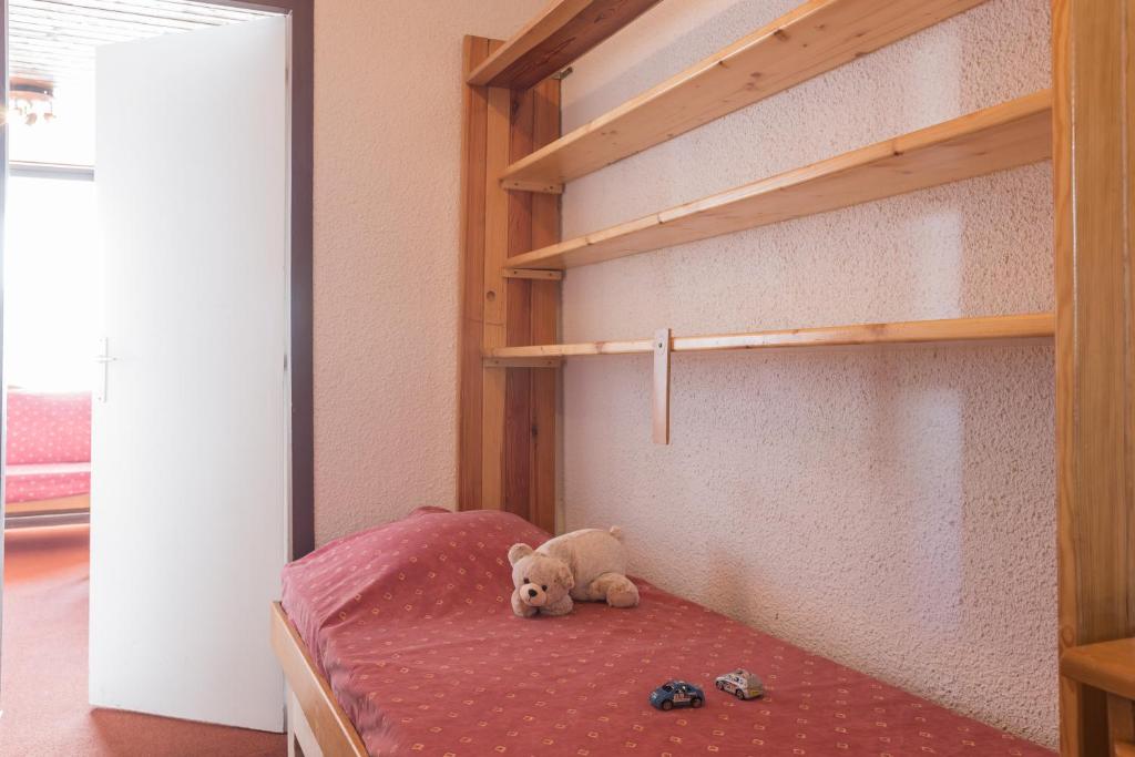 - un ours en peluche assis sur un lit dans une chambre dans l'établissement Résidence partenaire Le Schuss, à Val Thorens