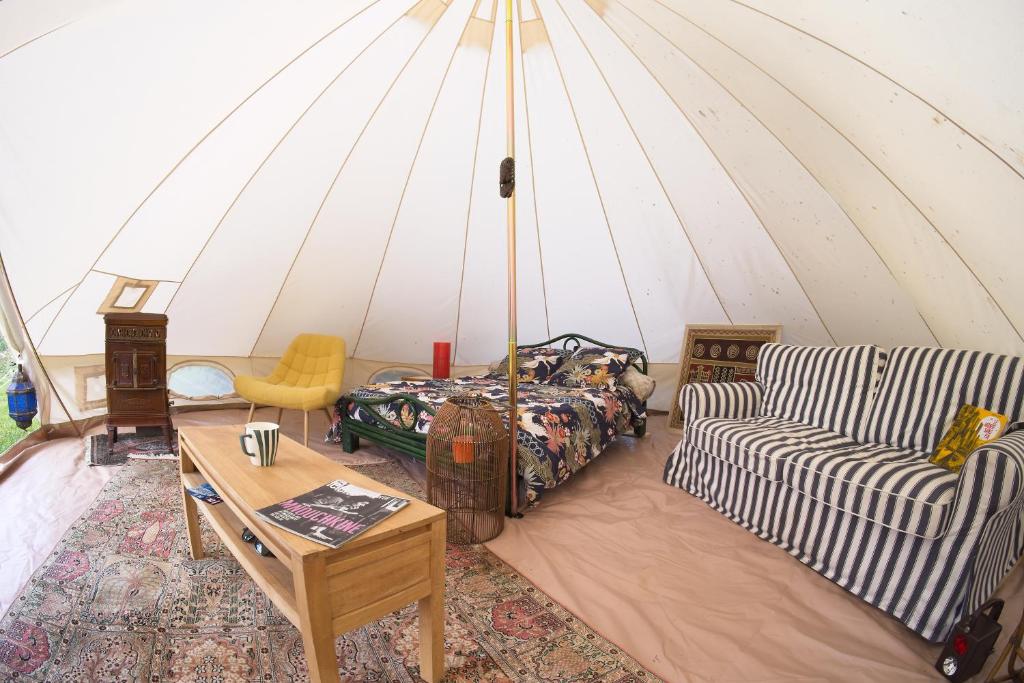Cette chambre comprend une tente avec un canapé et une table. dans l'établissement Tente mongole 4 saisons cosy et spacieux, à Conchy-les-Pots