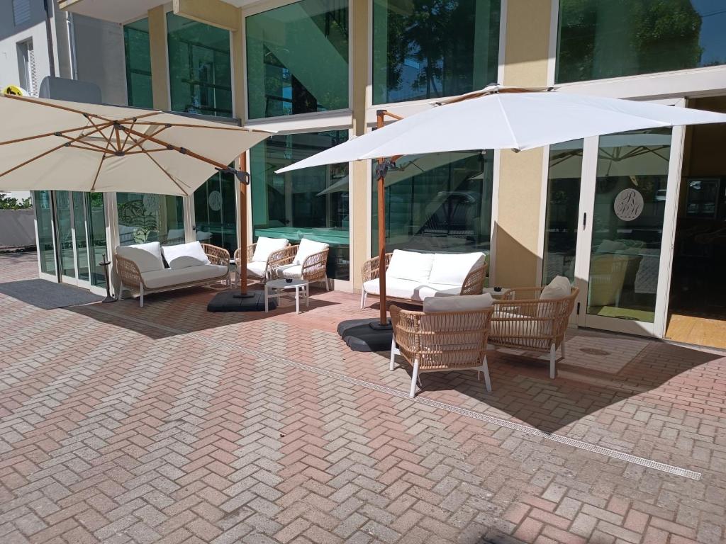 un patio avec des chaises et des parasols en face d'un bâtiment dans l'établissement Hotel Remin Plaza, à Rimini