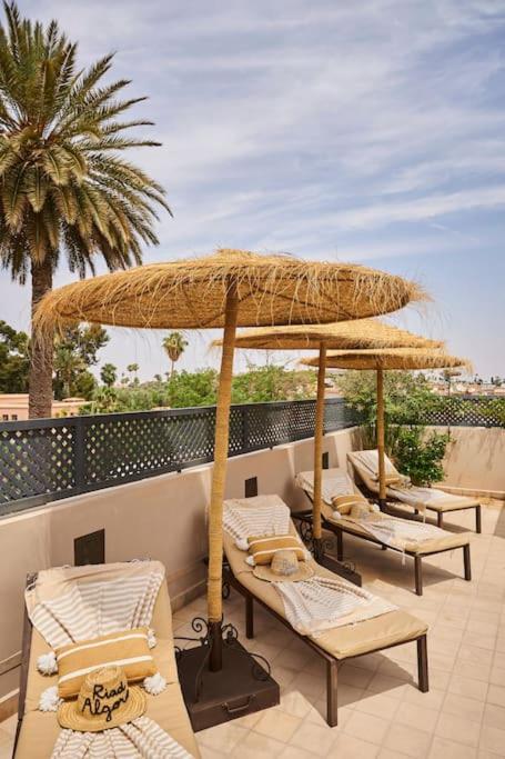 un groupe de chaises et un parasol sur une terrasse dans l'établissement Riad Algora en exclusivité 13 P au cœur de la Médina, à Marrakech