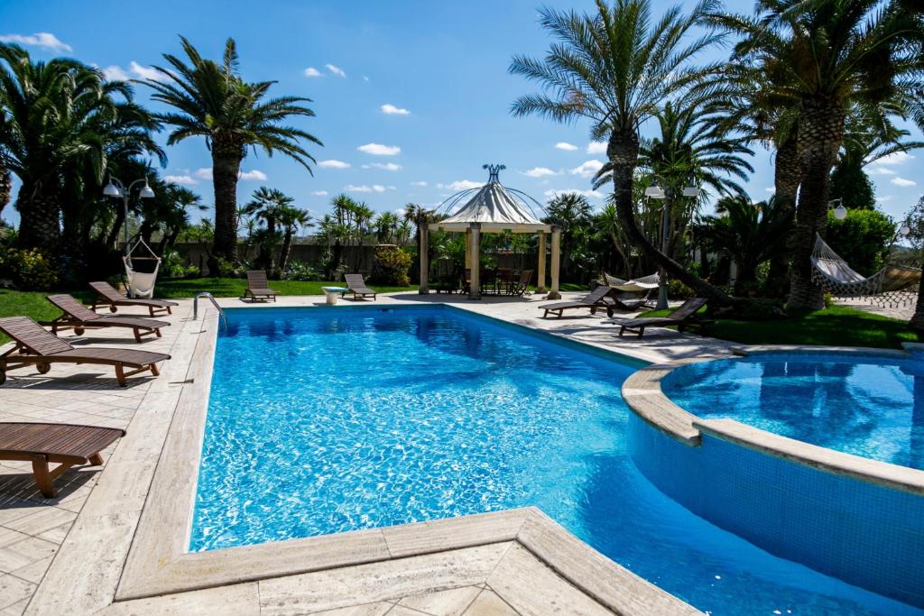 une piscine avec des chaises et un gazebo dans l'établissement Villa Incoronata, à Nardò