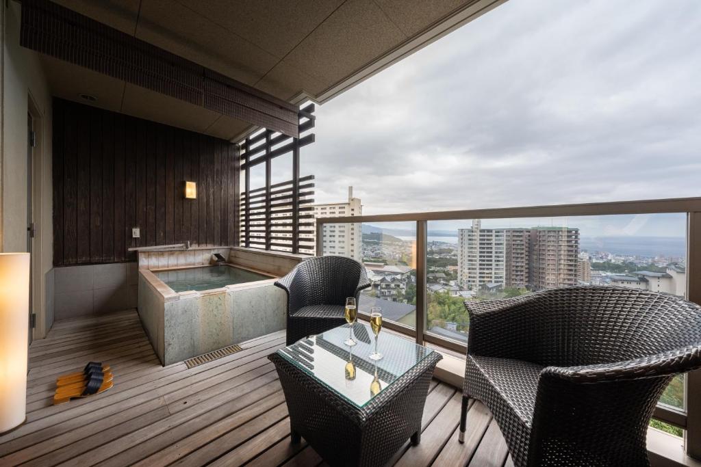 - un balcon avec un bain à remous et des chaises dans un bâtiment dans l'établissement Ryotei Matsubaya, à Beppu