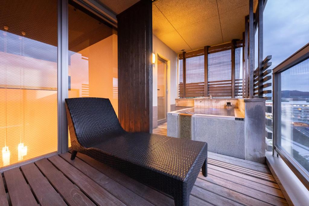 une chaise en osier assise sur un balcon avec fenêtre dans l'établissement Ryotei Matsubaya, à Beppu