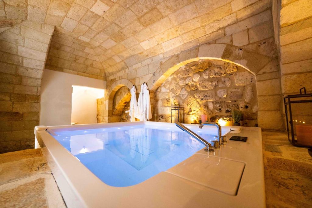 Cette chambre dispose d'une grande baignoire et d'un mur en pierre. dans l'établissement Vecchia Mottola WELLNESS, à Mottola