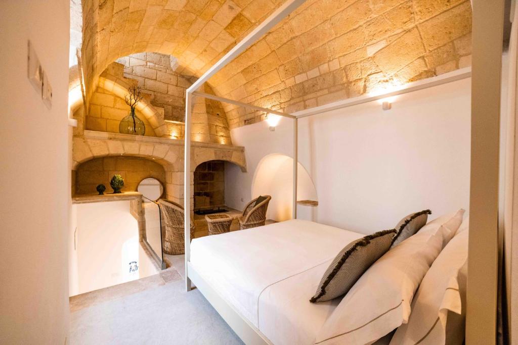 - une chambre avec un lit blanc dans une pièce dotée d'un mur en briques dans l'établissement Vecchia Mottola WELLNESS, à Mottola
