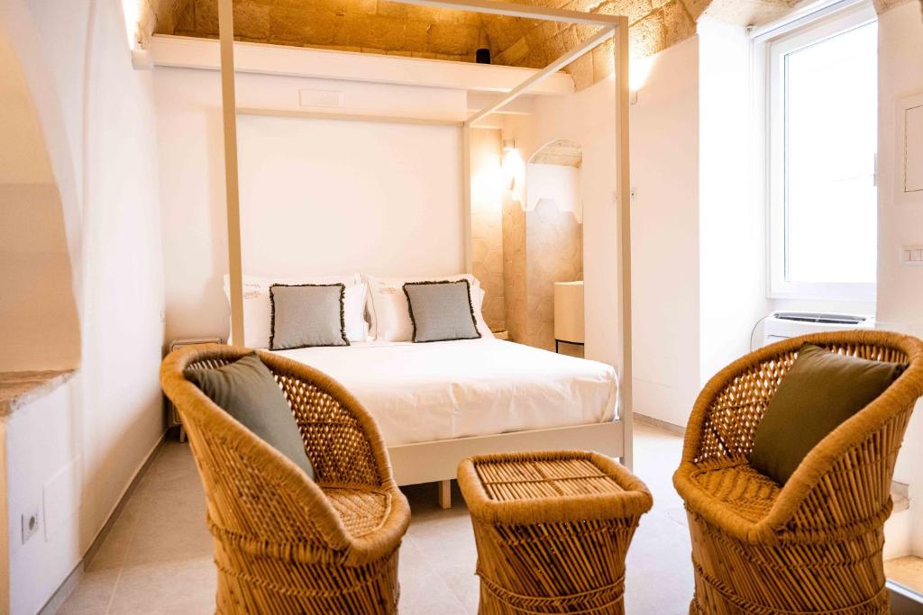 - une chambre avec un lit et deux chaises en osier dans l'établissement Vecchia Mottola WELLNESS, à Mottola