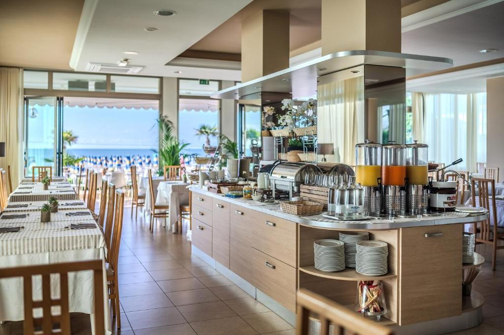 un restaurant avec un bar avec tables et chaises dans l'établissement Hotel Orizzonte, à Lido di Jesolo