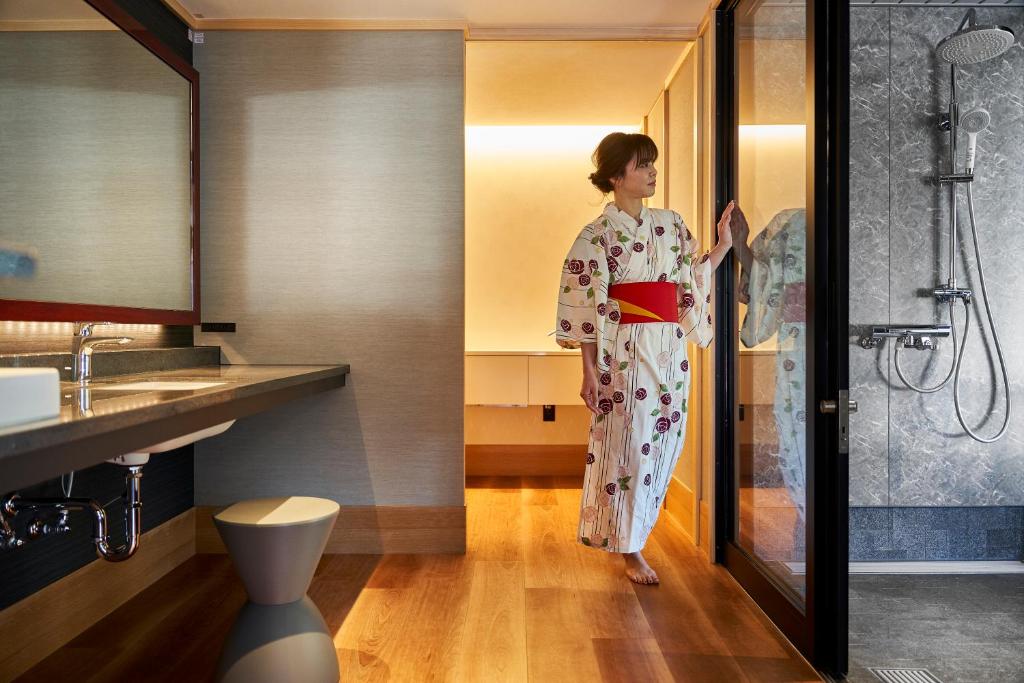 une femme en kimono debout dans une salle de bains dans l'établissement Mansuirou, à Misasa