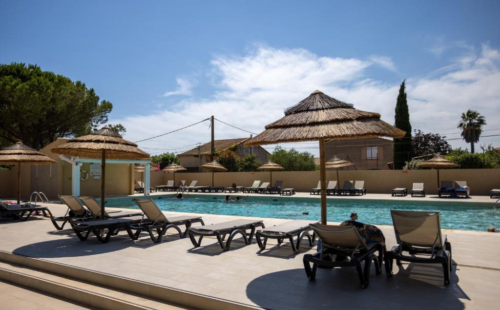 - une piscine avec des chaises longues et des parasols à côté d'un complexe dans l'établissement Camping maeva Escapades Le Hameau des Pins, à La Crau