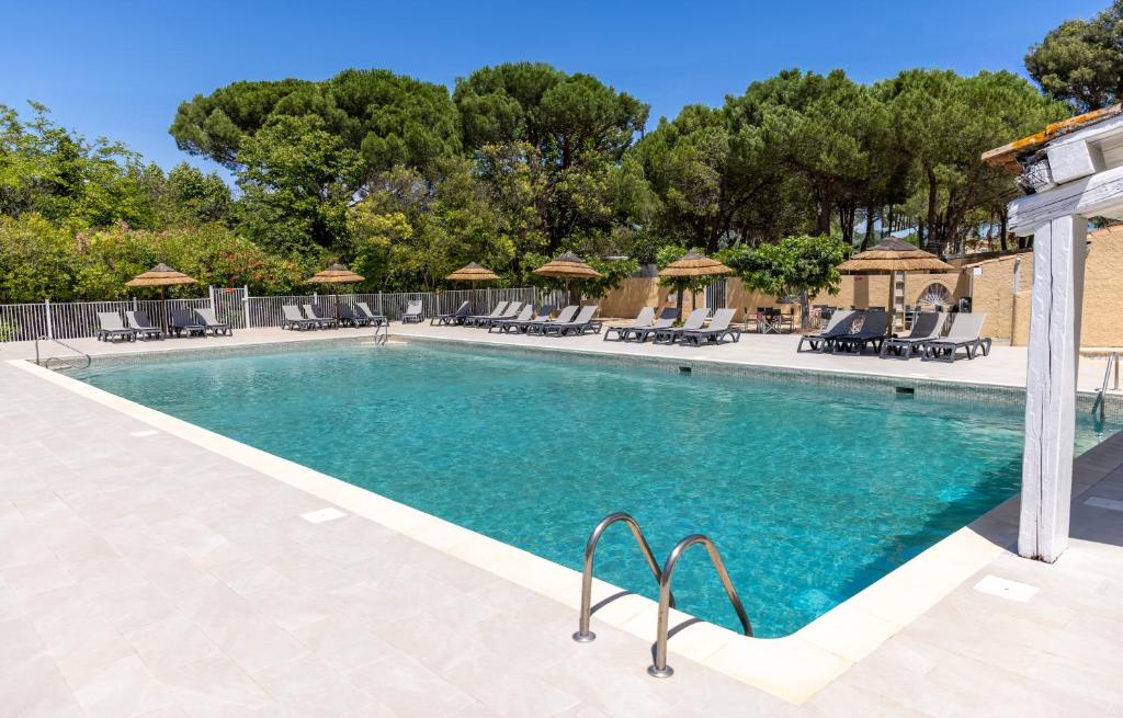 - une piscine dans un complexe avec des chaises et des arbres dans l'établissement Camping maeva Escapades Le Hameau des Pins, à La Crau