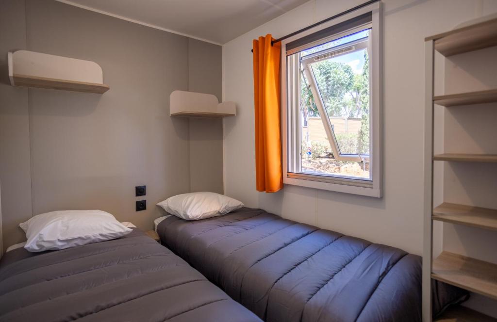 deux lits dans une chambre avec une fenêtre dans l'établissement Camping maeva Escapades Le Hameau des Pins, à La Crau