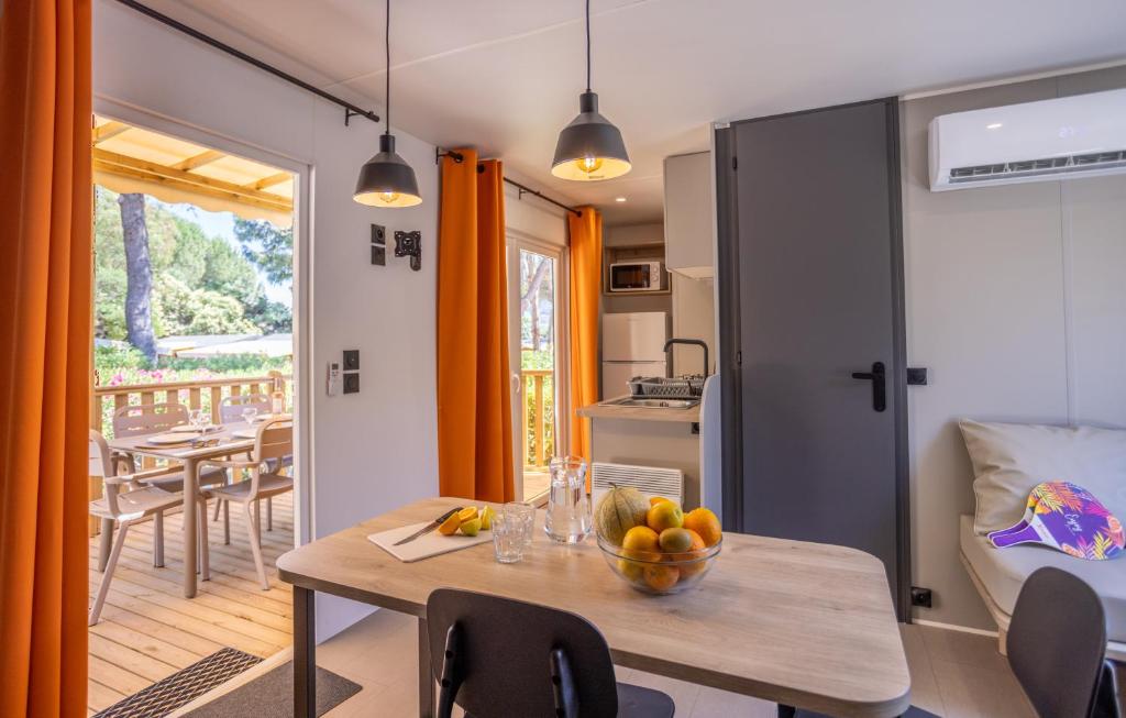 - une cuisine et une salle à manger avec une table et un bol de fruits dans l'établissement Camping maeva Escapades Le Hameau des Pins, à La Crau