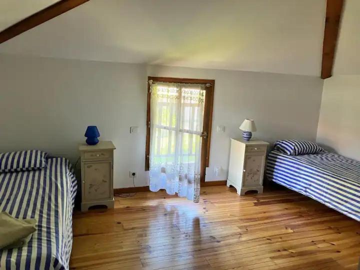 - une chambre avec 2 lits, une fenêtre et du parquet dans l'établissement Gîte du Maou - Maison avec piscine, à Lesperon