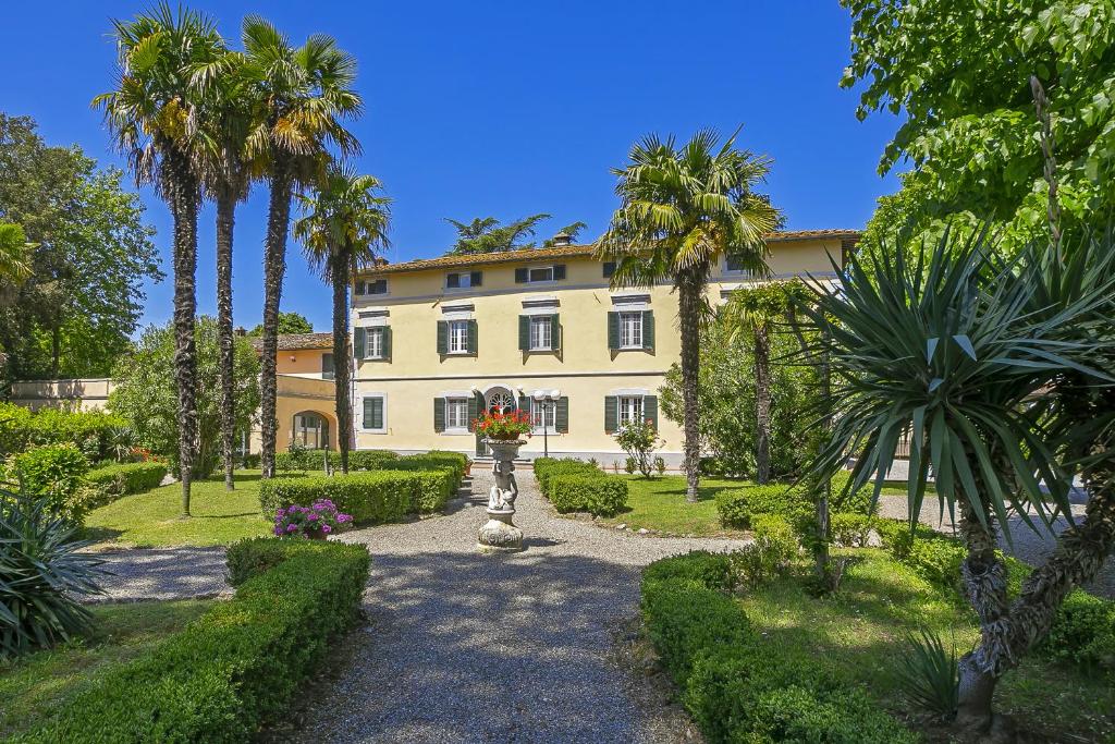un bâtiment avec des palmiers en face d'un jardin dans l'établissement Tenuta Santa Colomba - Happy Rentals, à Montecalvoli